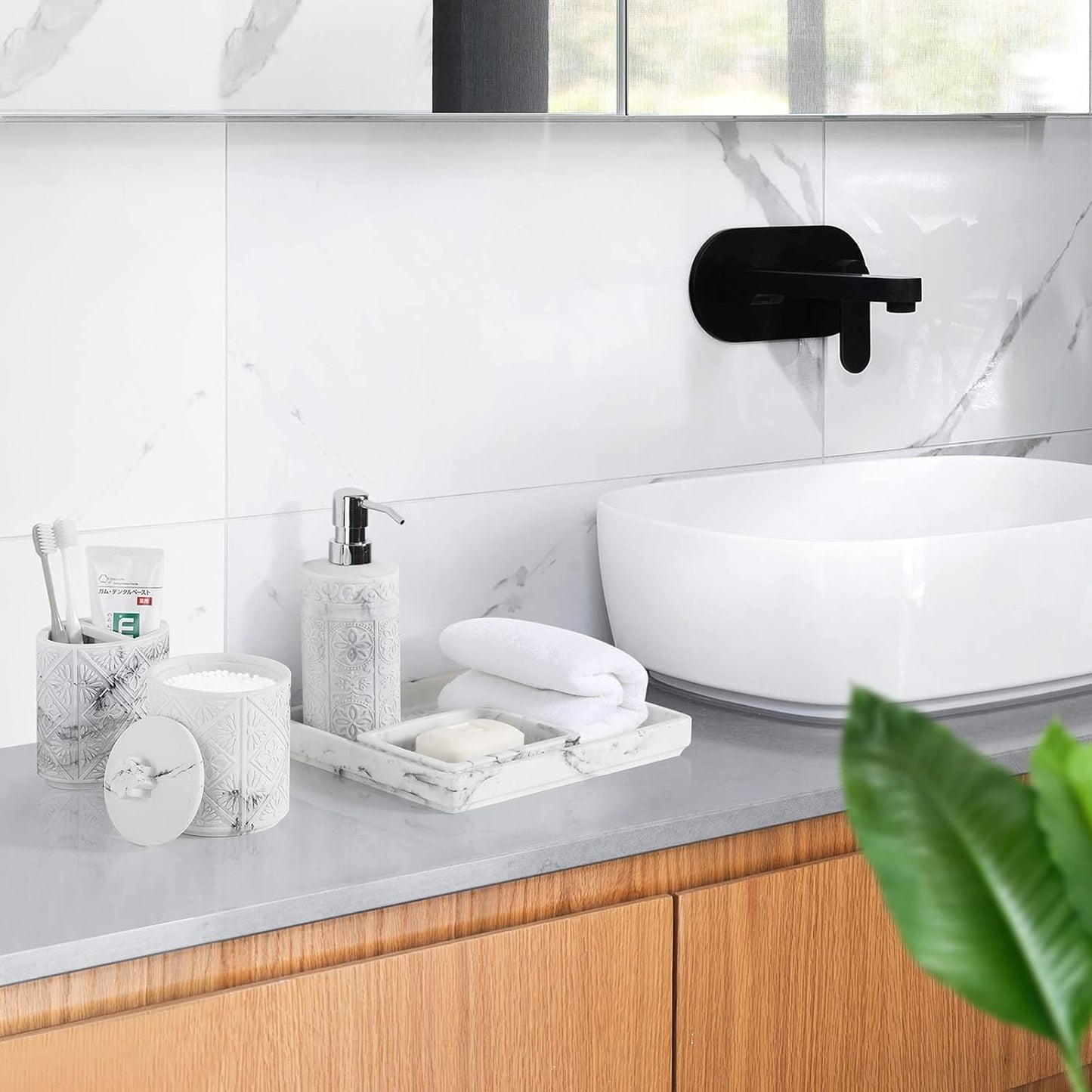 Bathroom accessories set on a modern countertop featuring a soap dispenser, toothbrush holder, and decorative tray.