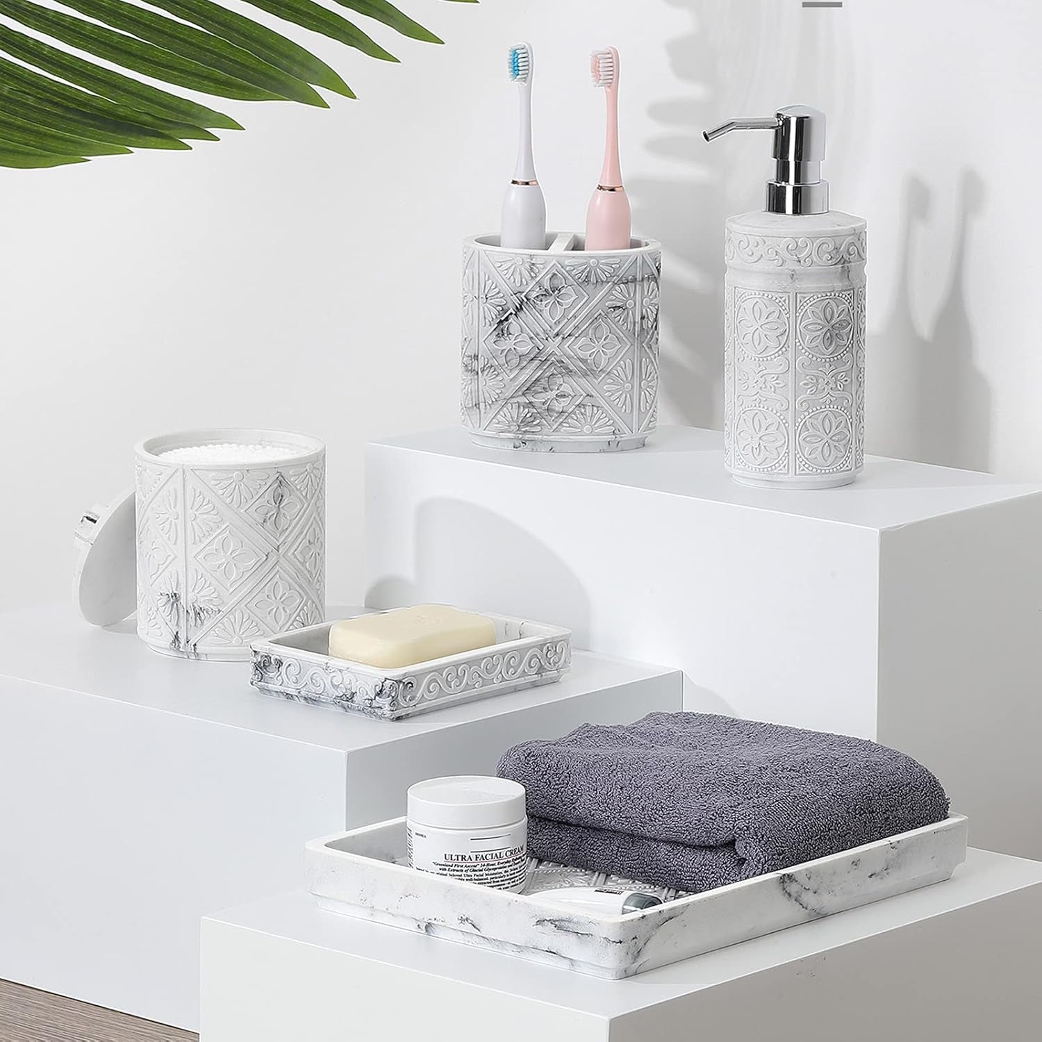 Bathroom accessories set showcasing decorative resin pieces including a soap dispenser, toothbrush holder, and tray.